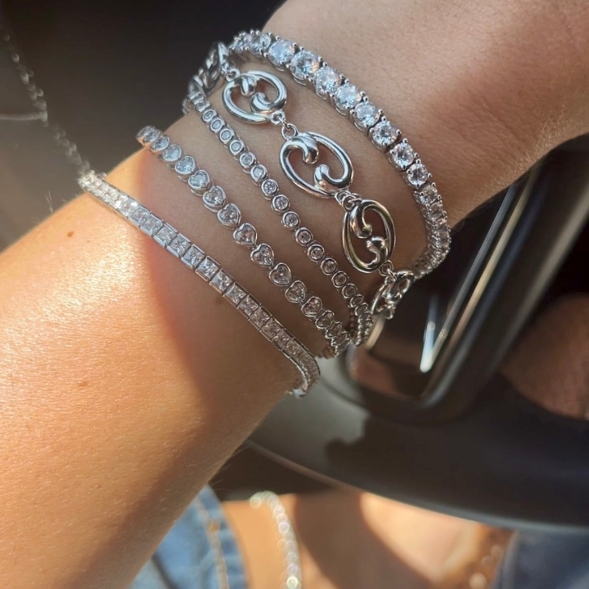 Close-up of a wrist wearing multiple silver tennis bracelets and Fibonacci spiral
