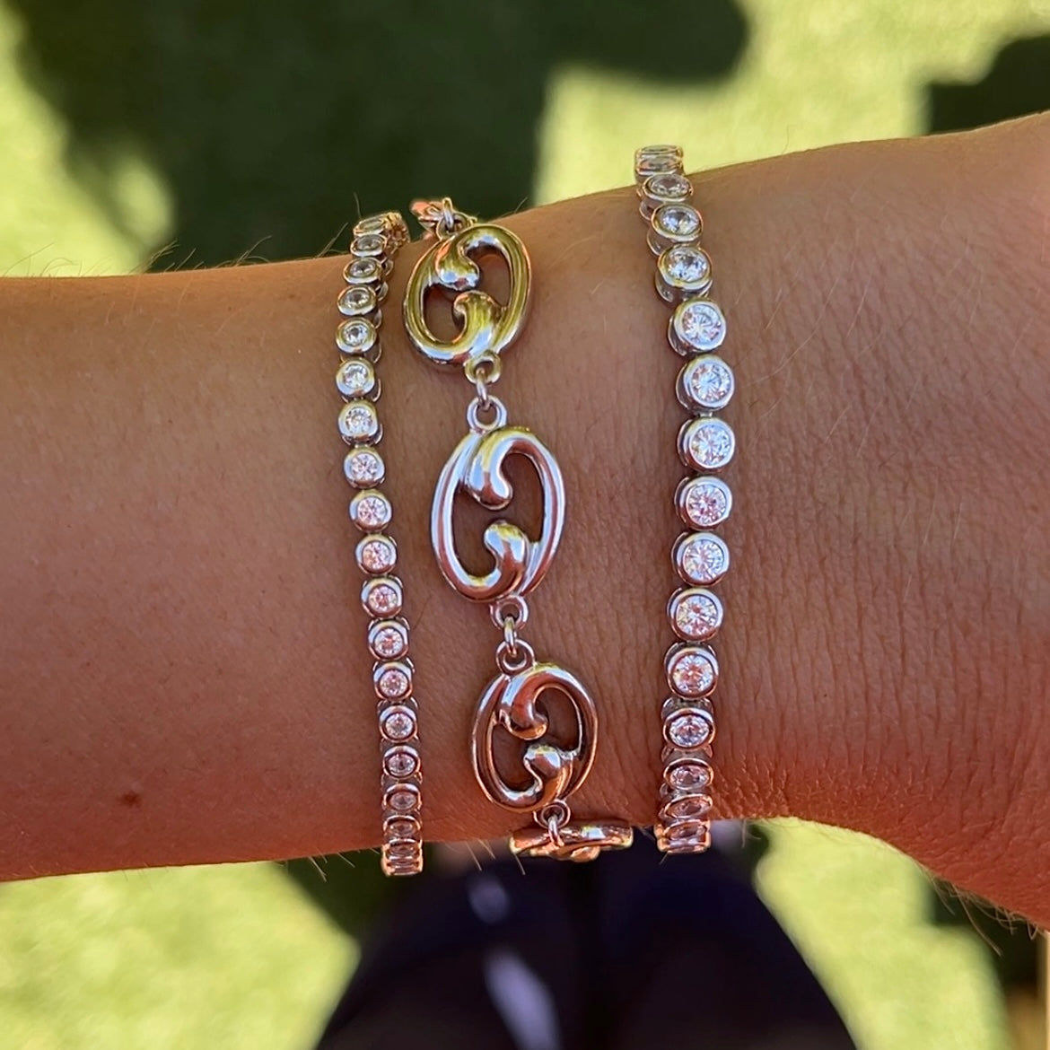 Our Fibonacci spiral bracelet with two of our round bezel tennis bracelets shown on a wrist