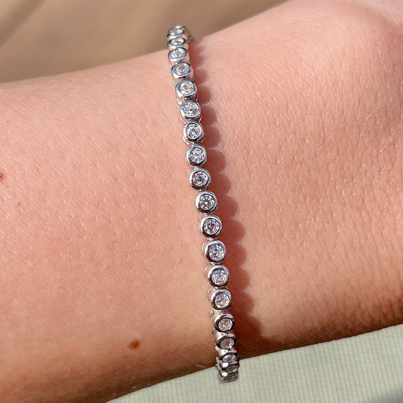 Our 2mm bezel tennis bracelet shown on wrist in the sunlight 