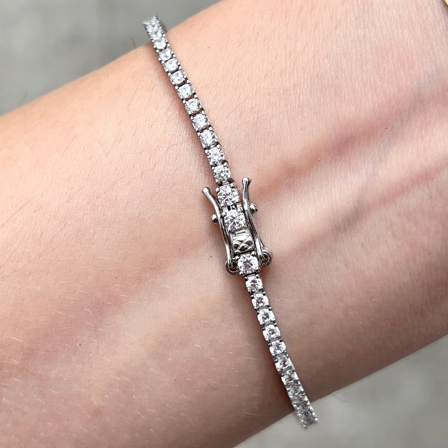 Closeup of the clasp our sterling silver 4 prong 2mm thin tennis bracelet on a wrist