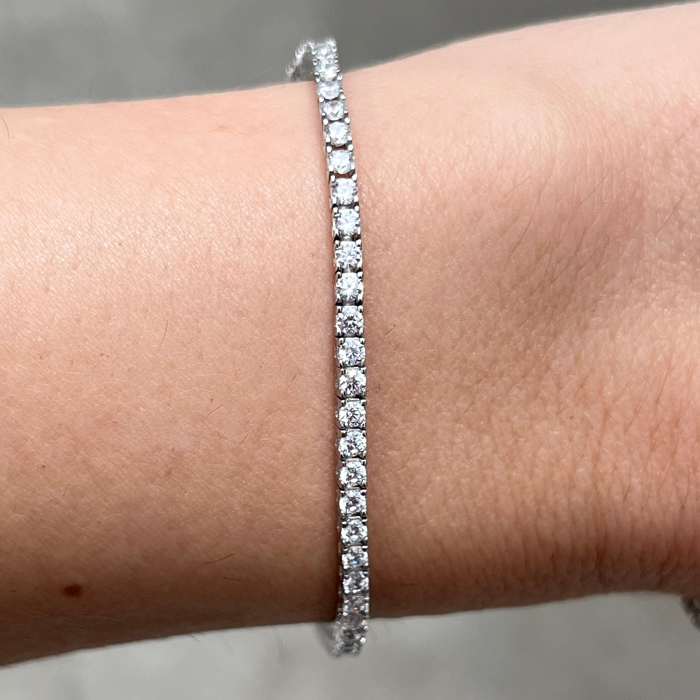 Closeup of our sterling silver 4 prong 2mm thin tennis bracelet on a wrist