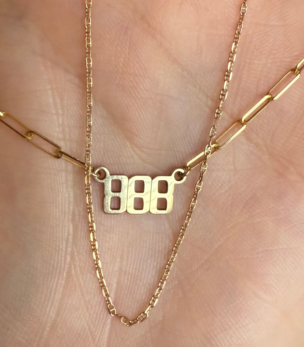 Gold necklace with a '888' pendant on a hand
