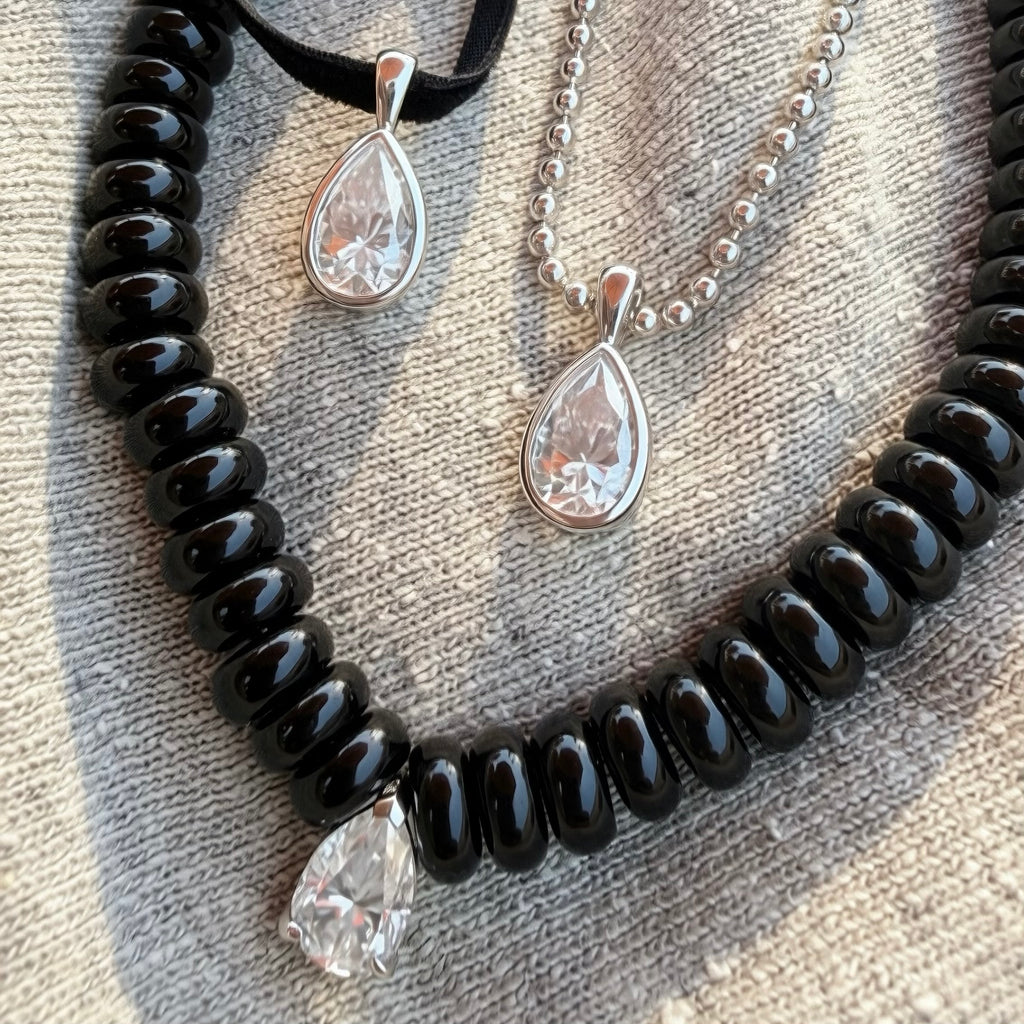 A black agate beaded necklace with moissanite pear drop and two pear shaped moissanite pendants