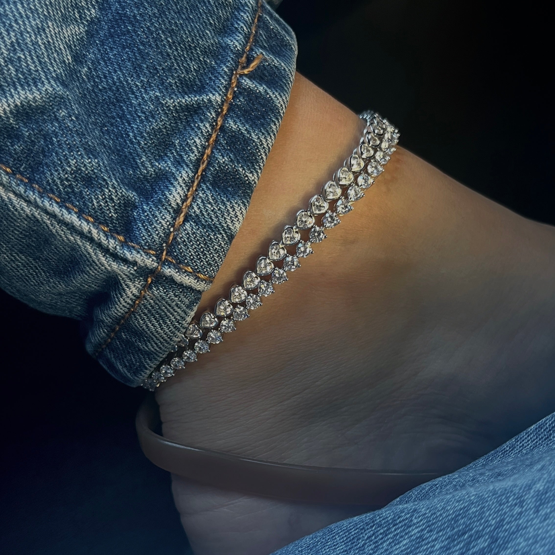 Diamond tennis anklet bracelet on an ankle with denim jeans