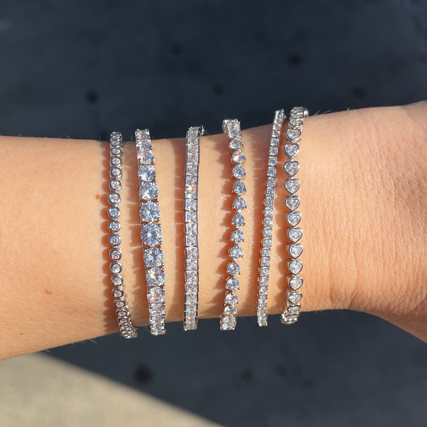 Six faux tennis bracelets show on a wrist in the sunlight