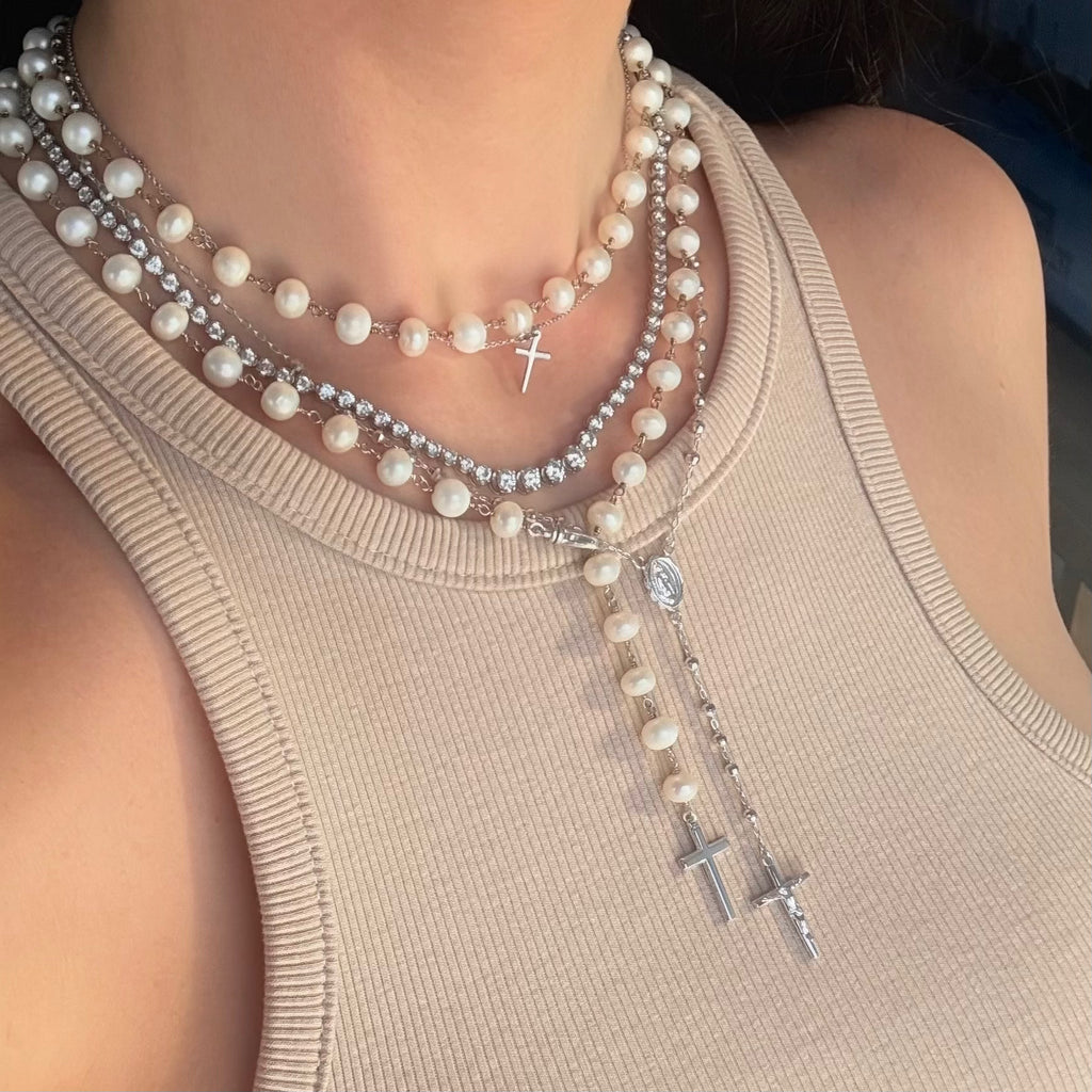 Graduated tennis necklace layered with a pearl rosary necklace and a sterling silver rosary necklace 
