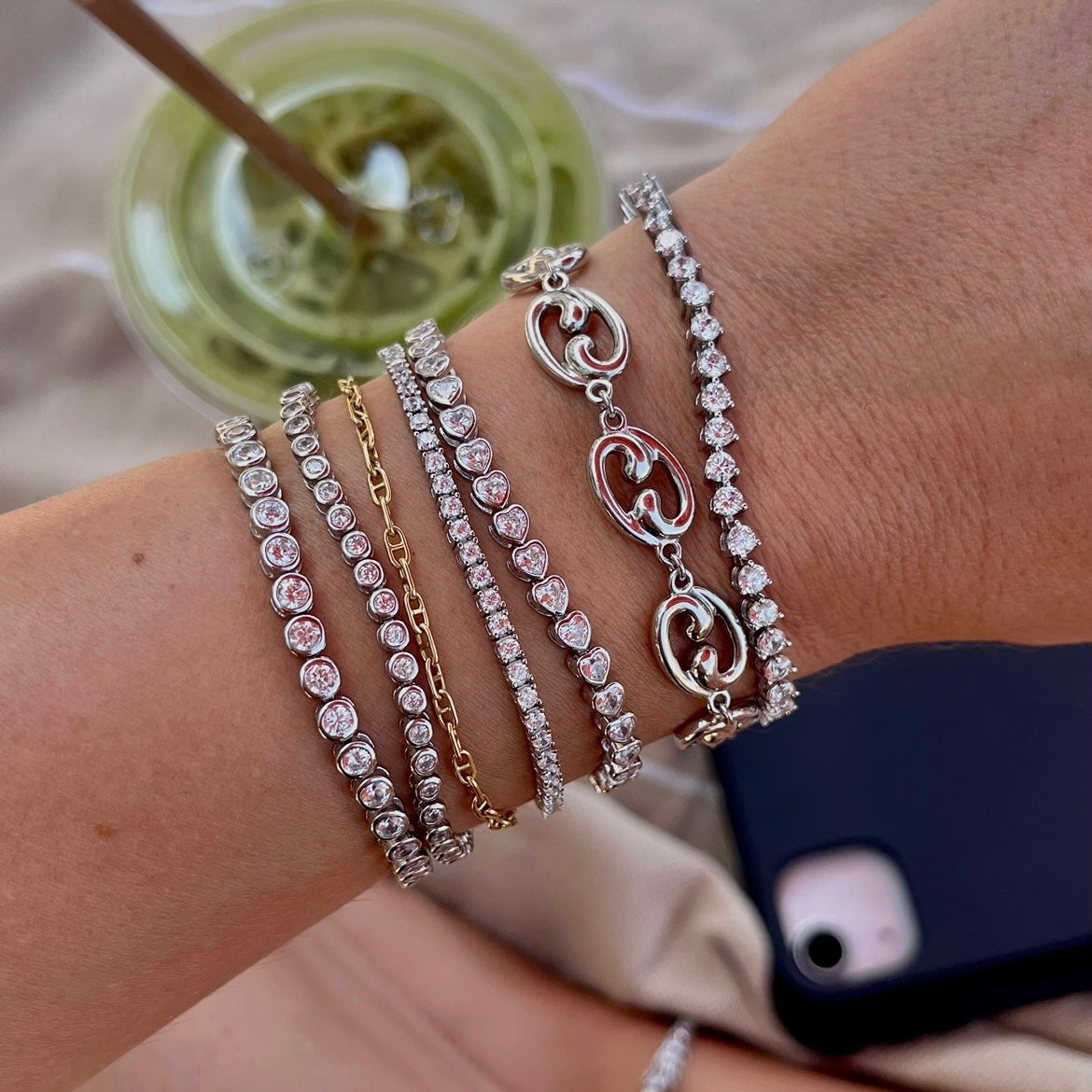 Stack of Leni James tennis bracelets on a wrist with a Fibonacci spiral link silver bracelet 