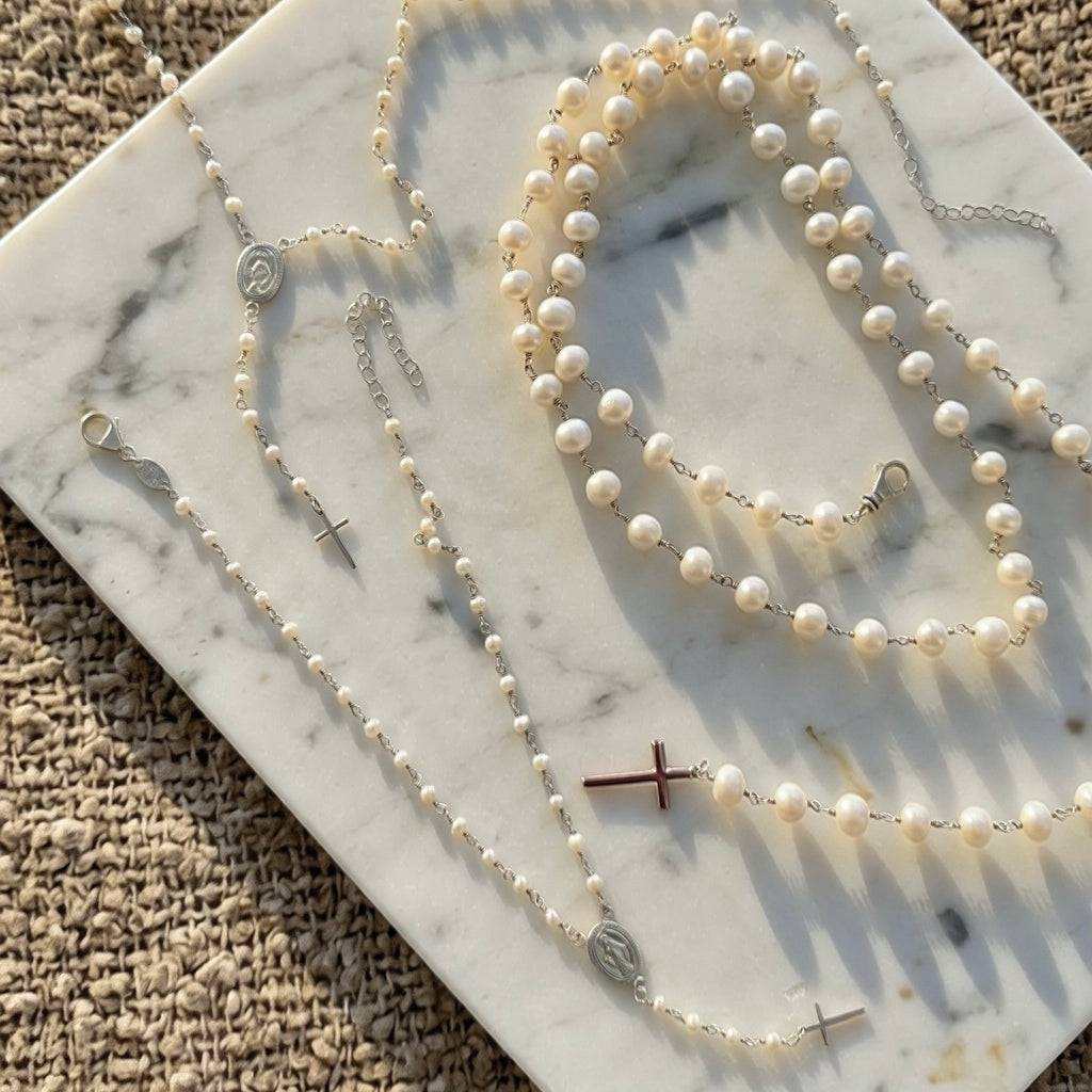 Pearl rosary necklaces displayed on marble