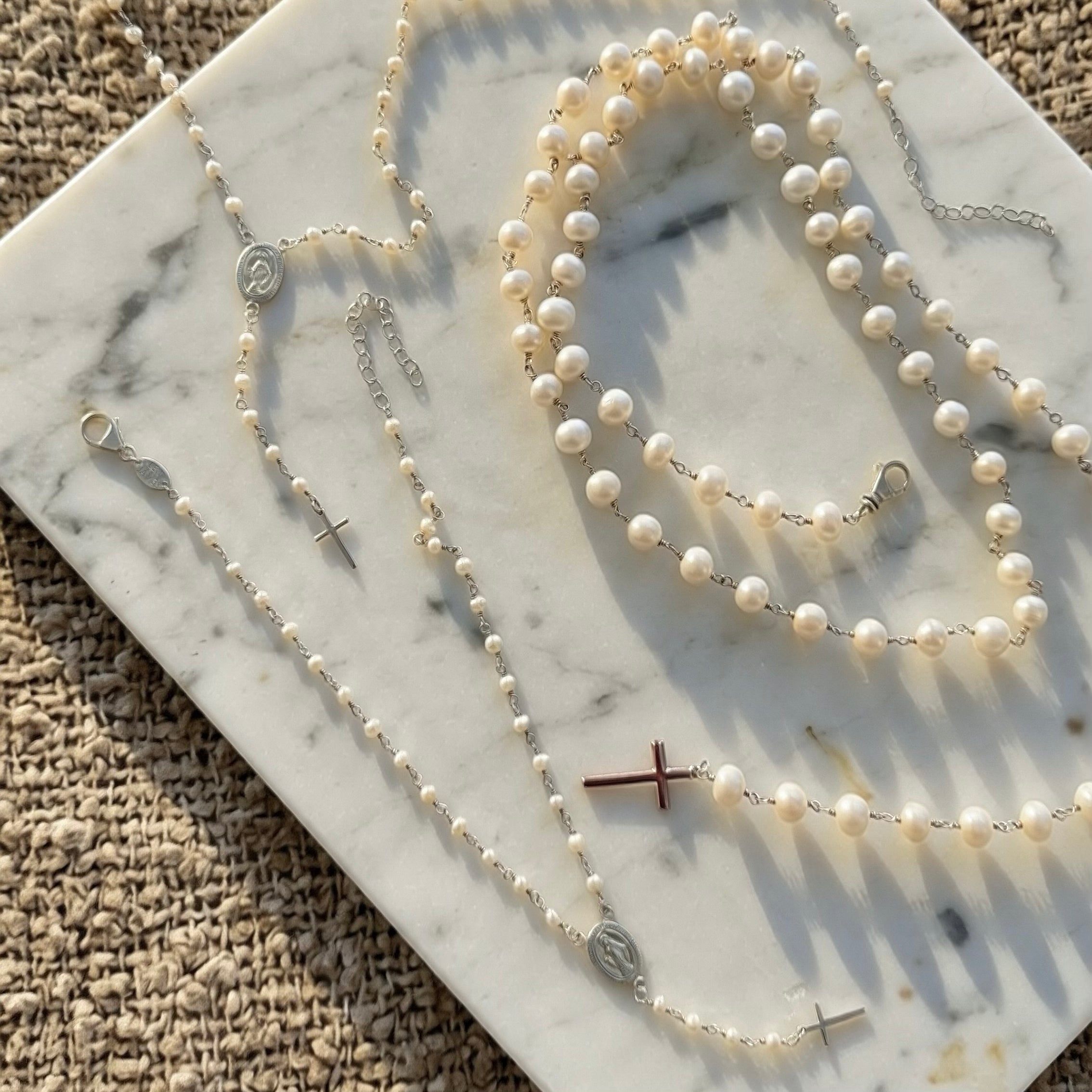 Pearl rosary necklaces displayed on marble