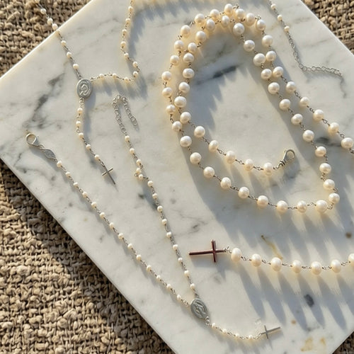 Pearl rosary necklaces displayed on marble