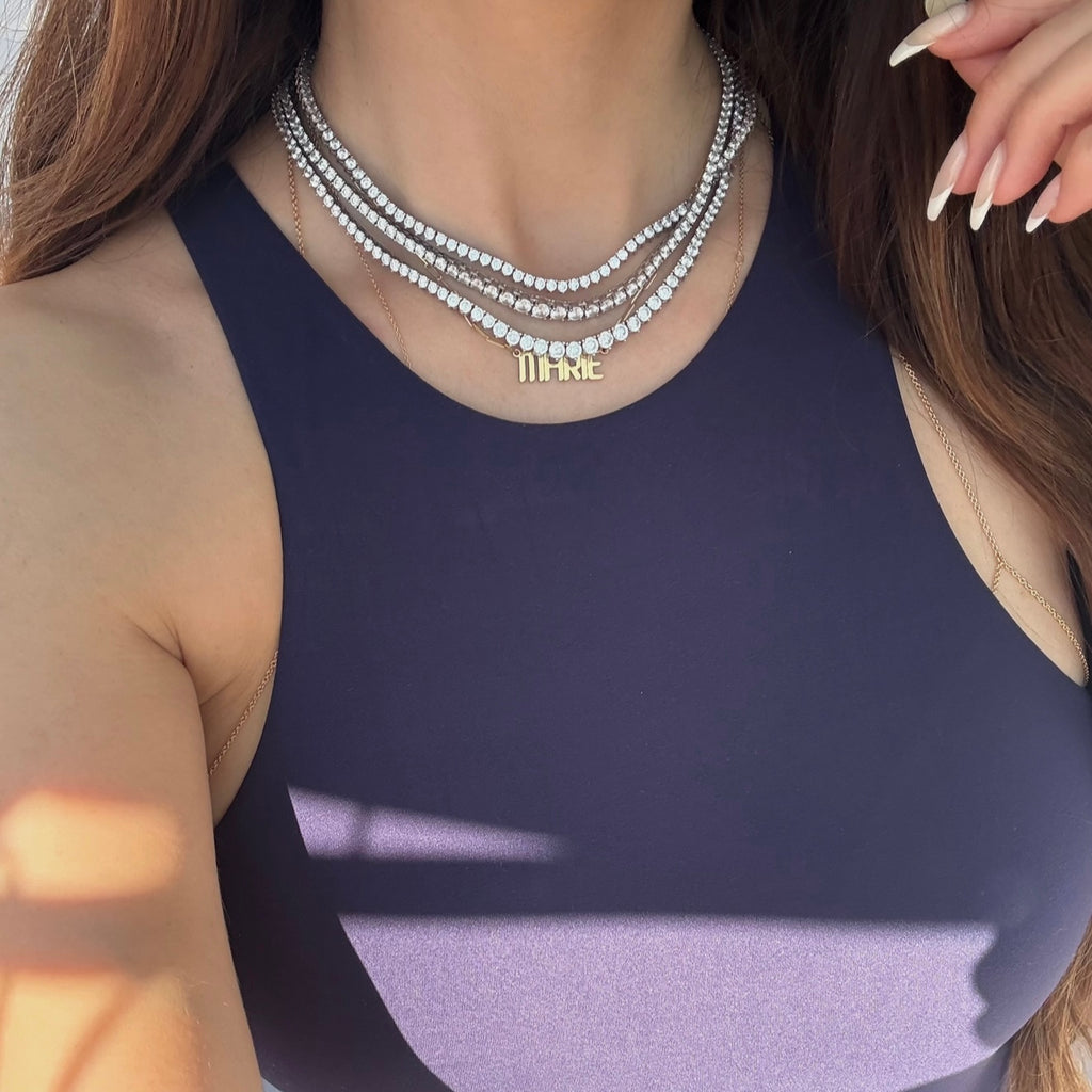 Woman wearing a stack of tennis necklaces with a focus on the jewelry.