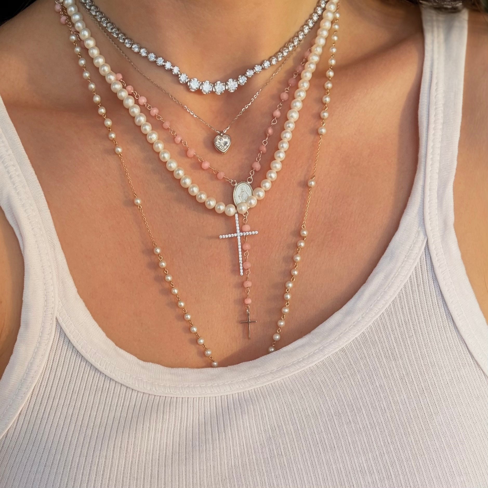 Pave cross pearl necklace styled with pink rosary and tennis necklace 