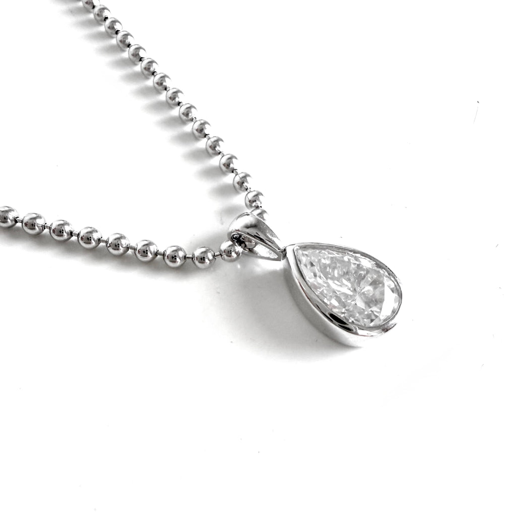 A silver ball chain necklace with a teardrop-shaped moissanite pendant in a sterling silver bezel setting