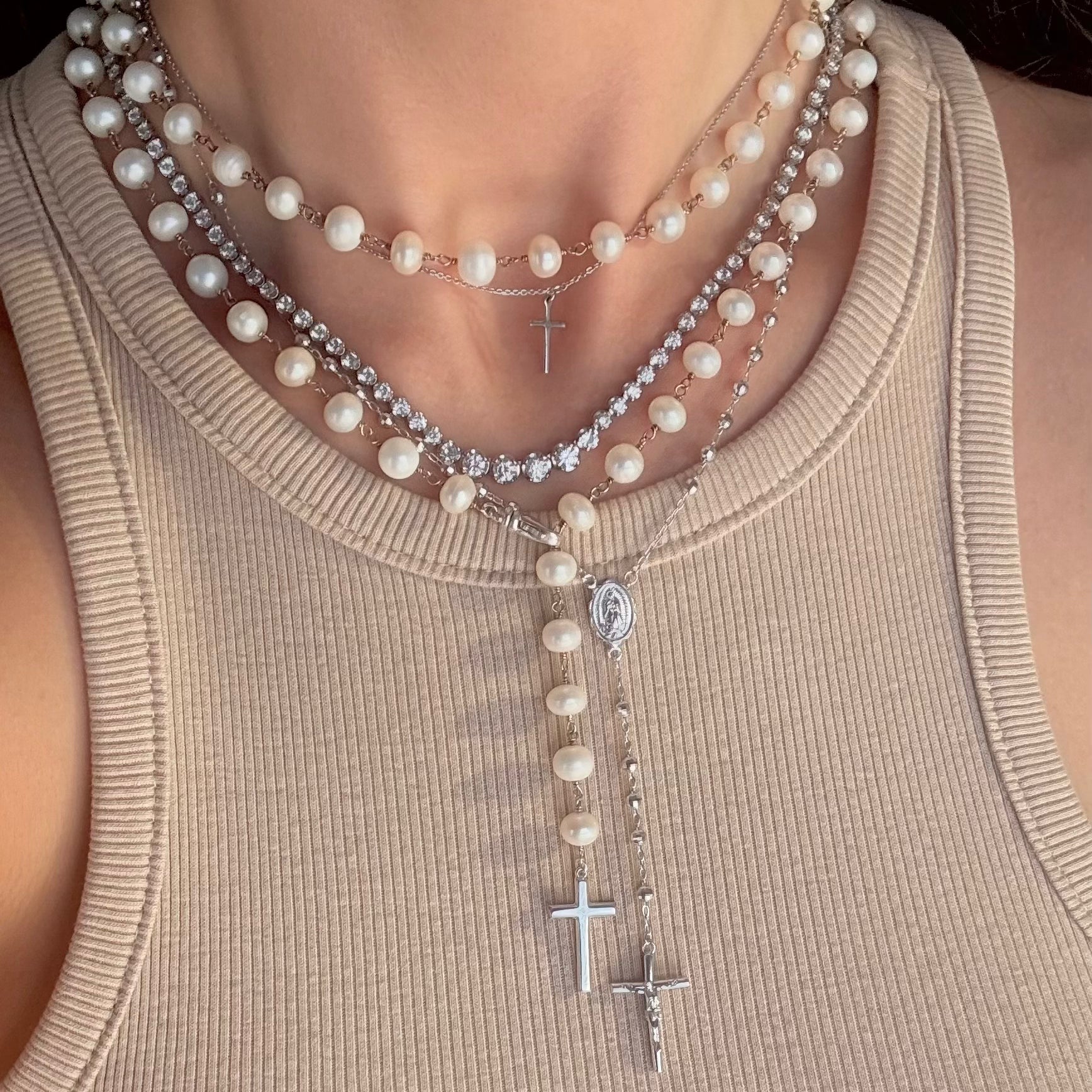 Layered rosary in silver and rosary necklaces with freshwater pearls and a tennis necklace 