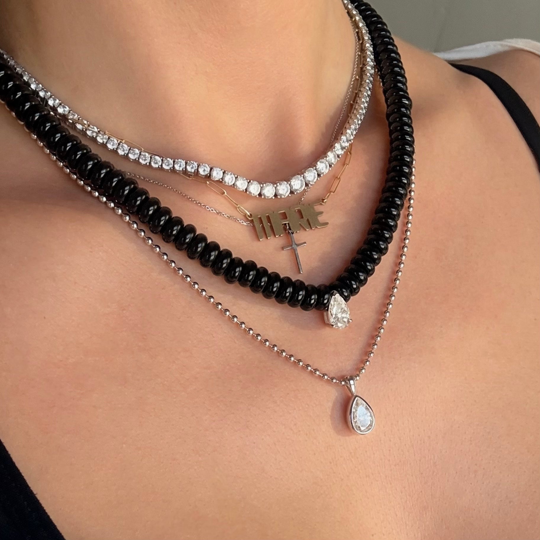 Layered tennis necklace with a black agate beaded necklace and moissanite pear shaped drop pendant
