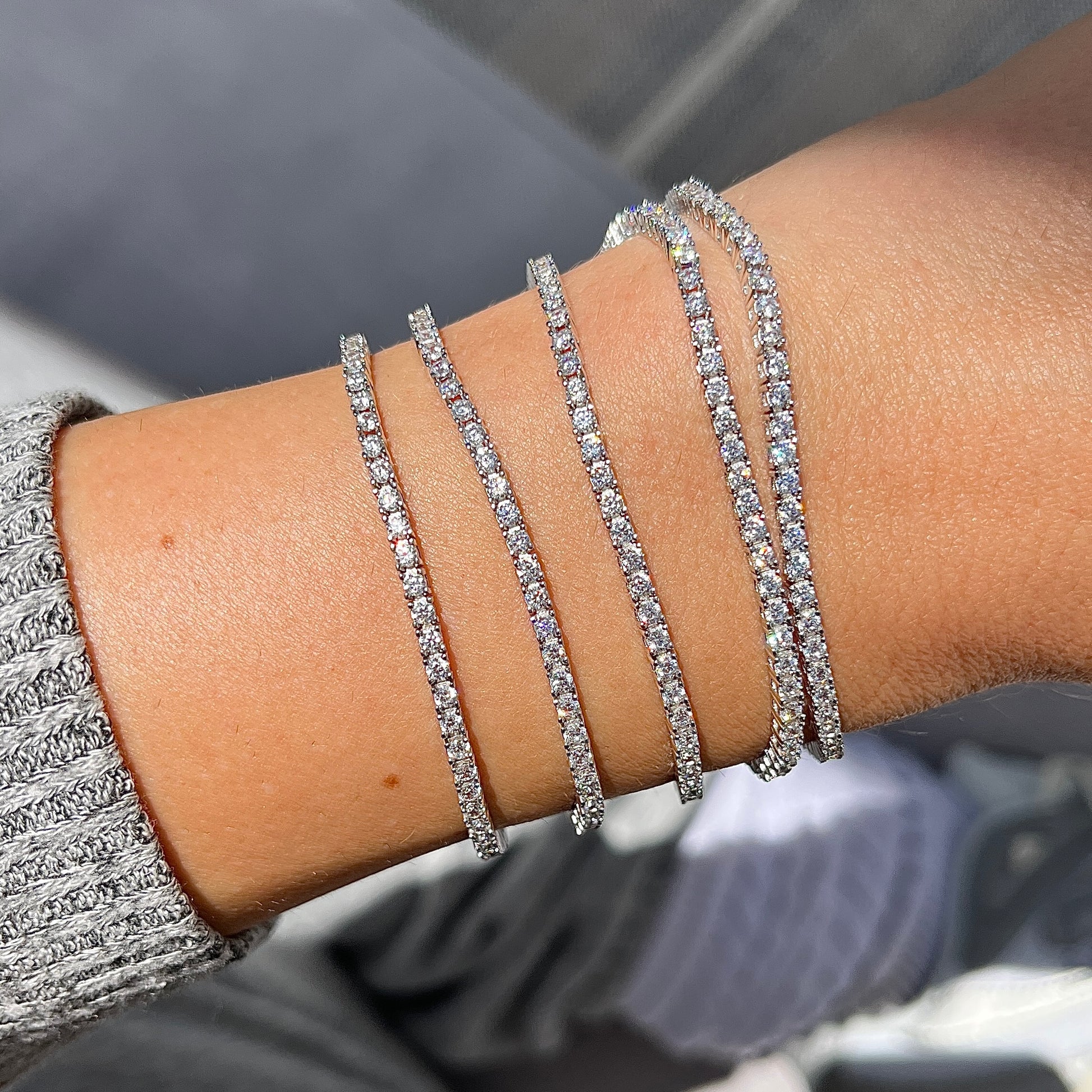 Five thin Leni James tennis bracelets on a wrist with sunshine energy