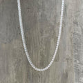 Closeup of our 2.5mm thin tennis necklace in zircon and sterling silver on concrete background