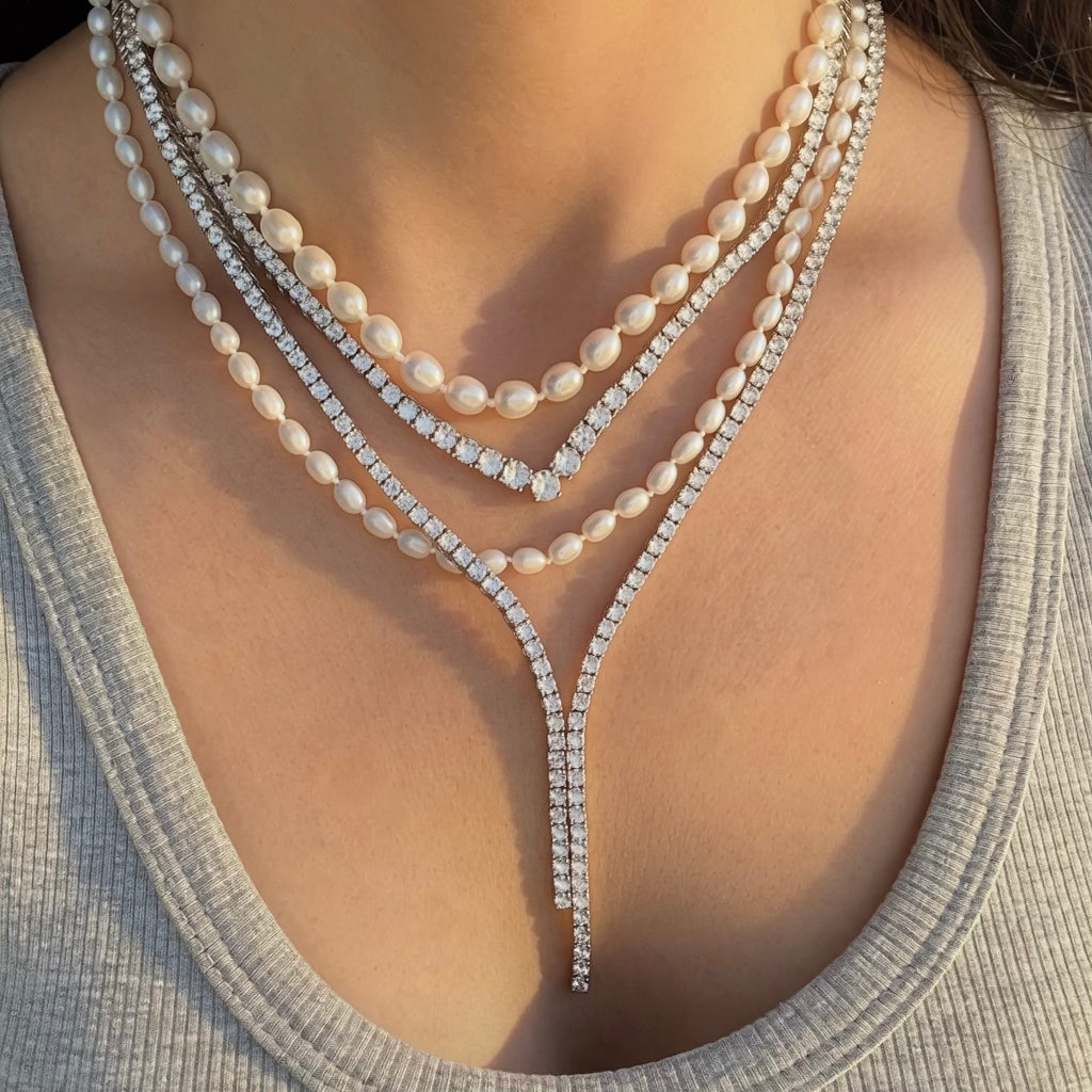 Pearl and diamond necklace worn by a person with a neutral background